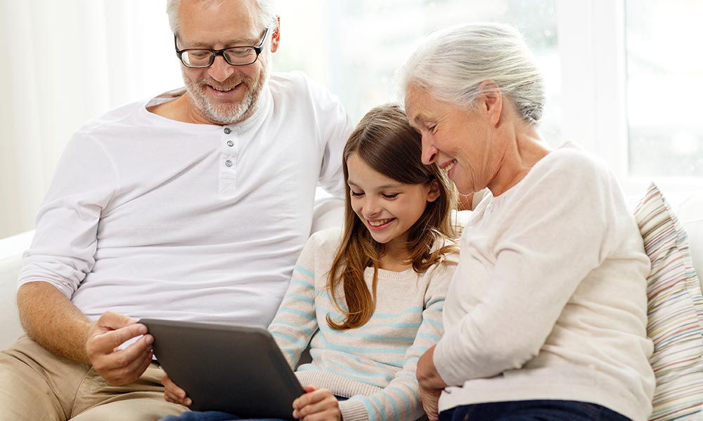 Retired couple using technology with their grandchild