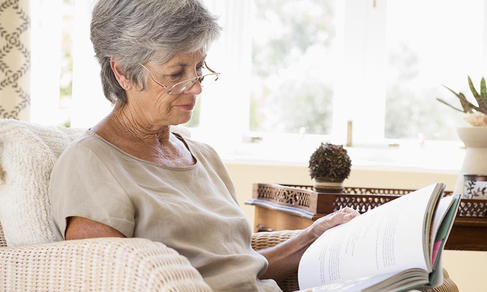 Retired woman reading a book in her apartment